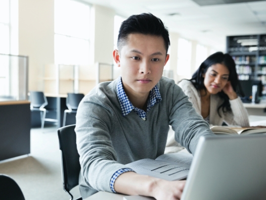 A photograph of a student on a laptop