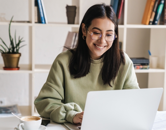student smiling and working on a laptop