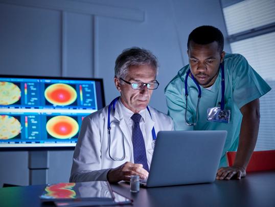 Doctors reviewing charts on laptop