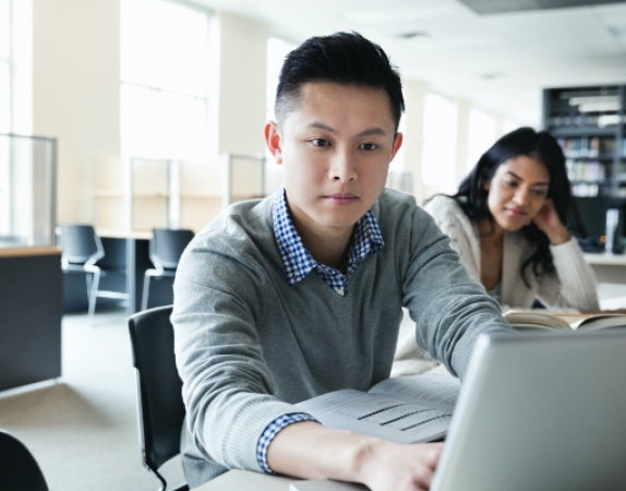 A photograph of a student on a laptop