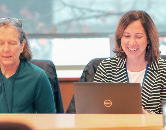 two people sitting at a table smiling and talking