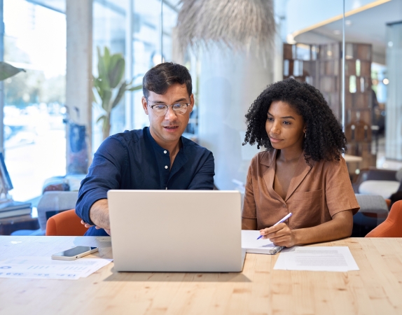 teacher pointing at laptop screen as student takes notes